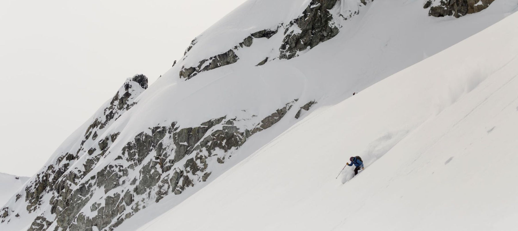 skier in deep snow with mountain cliffs behind