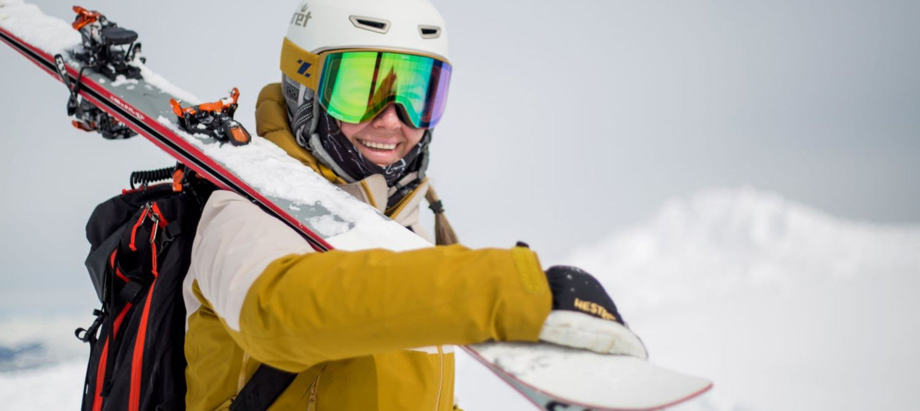 person smiling and holding skis